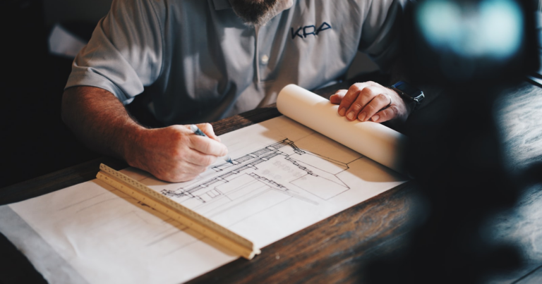 Architetto che disegna un progetto tecnico su carta con riga e matita, tema del codice ateco architetto ingegnere geometra forfettario