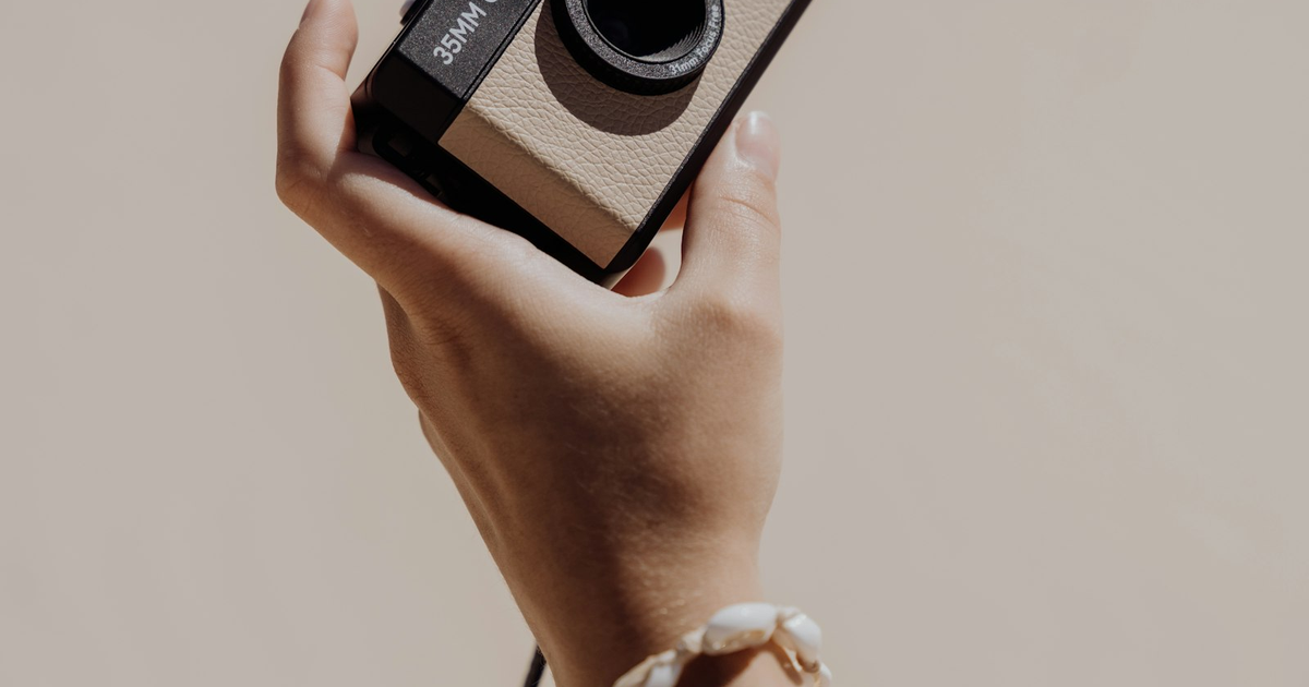 Mano che tiene una fotocamera vintage 35mm, tema del codice ateco fotografo forfettario